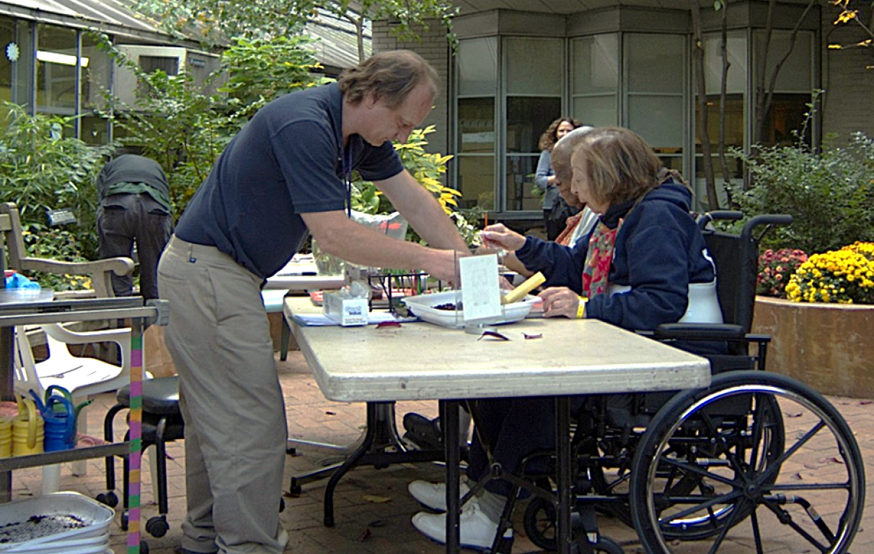 TH man and two women gardening at a table outdoors