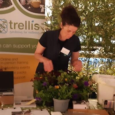 Trellis staff member at event stall surrounded by plants