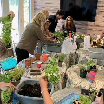 woman holding up herb pot in group around table